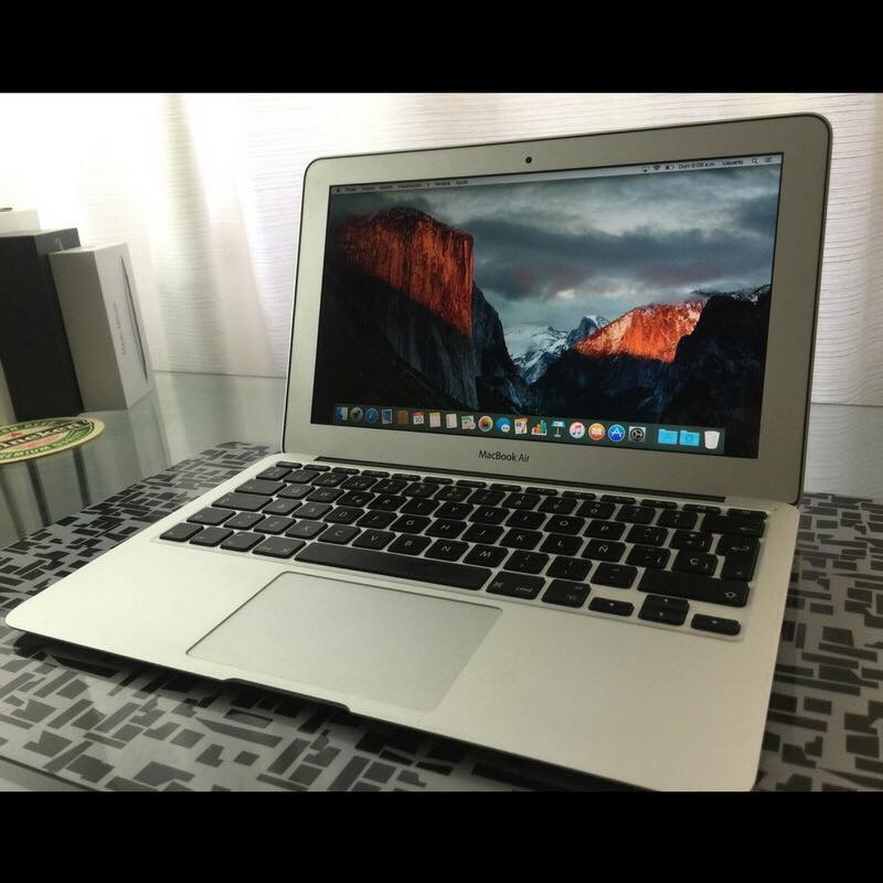 A silver laptop open on a desk with its screen lit and its box behind